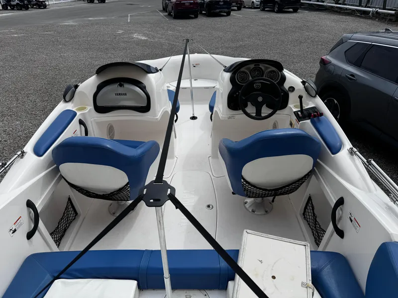 Slide: The Image of 2003 Yamaha Boats 210LX interior with blue seating and steering wheel, parked on gravel. - 4
