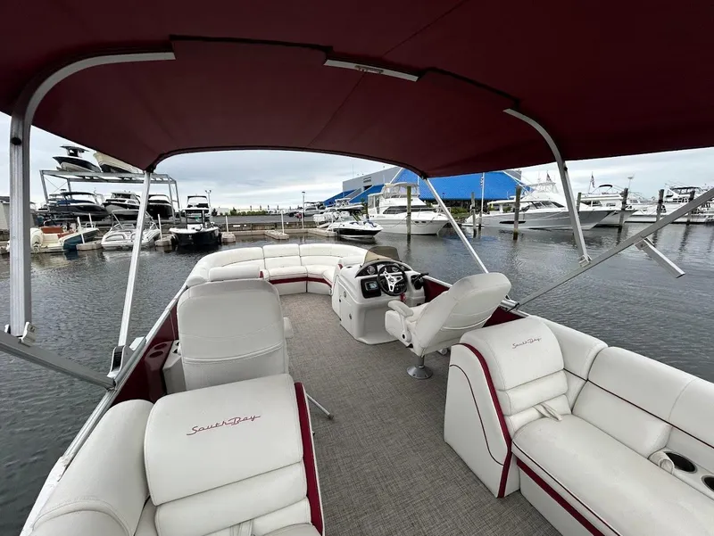 Slide: The Image of 2017 South Bay 500RS pontoon boat interior at marina, featuring white seating and red canopy. - 15