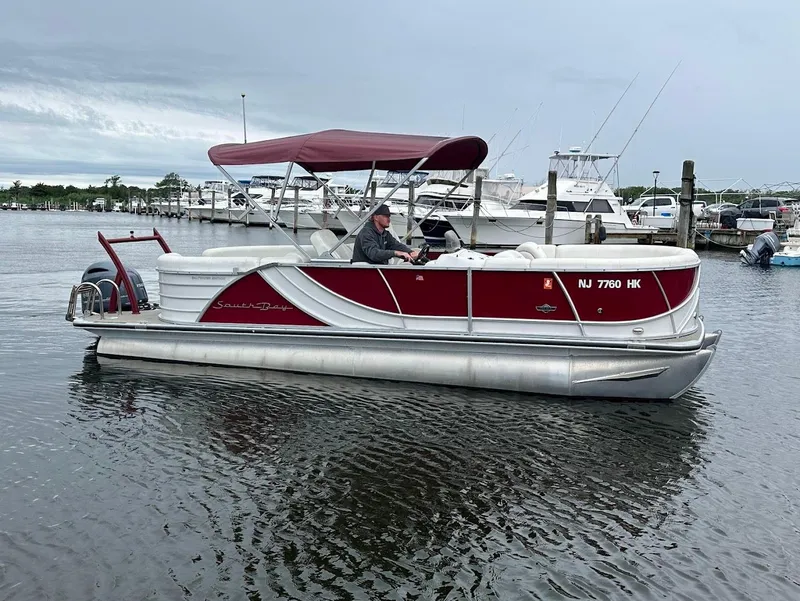 Slide: The Image of 2017 South Bay 500RS pontoon boat on water, red canopy, marina background. - 2