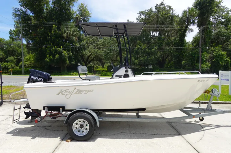 Slide: The Image of 2022 Key Largo 1800 Center Console boat on trailer, outdoors with trees in background. - 4