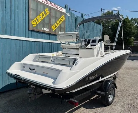 Slide: The Image of 2017 Yamaha Boats 190 FSH Deluxe on trailer, parked near blue building. - 3