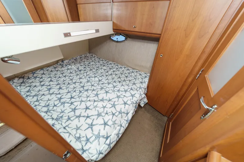 Slide: The Image of 2004 Silverton 38 Convertible cabin with starfish-patterned bedding and wooden cabinetry. - 20