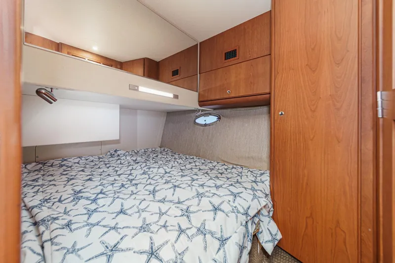 Slide: The Image of 2004 Silverton 38 Convertible cabin with starfish-patterned bedding and wooden cabinetry. - 21