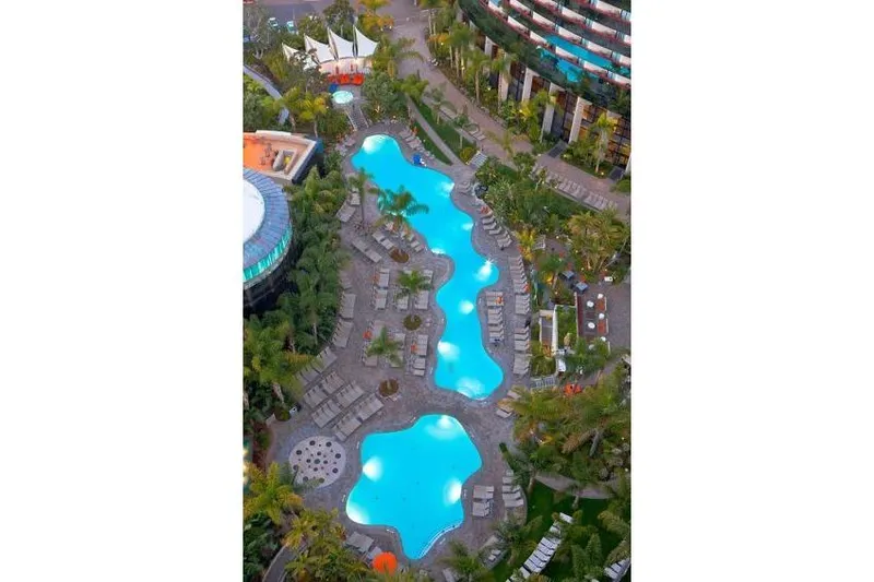 Slide: The Image of Aerial view of a luxurious, winding outdoor pool surrounded by lush greenery and lounge chairs. - 28