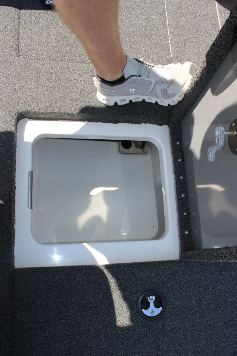 Slide: The Image of 2022 Caymas CX 18 SS boat deck with open storage compartment and foot in sneaker. - 14