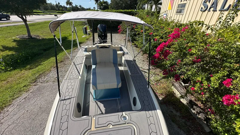 Slide: The Image of 2018 Outlaw 300R boat with canopy, parked near vibrant flowers and greenery. - 12