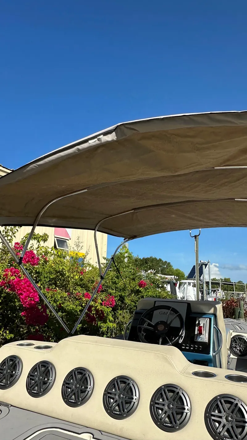 Slide: The Image of 2018 Outlaw 300R boat with canopy, speakers, and vibrant flowers in the background. - 4