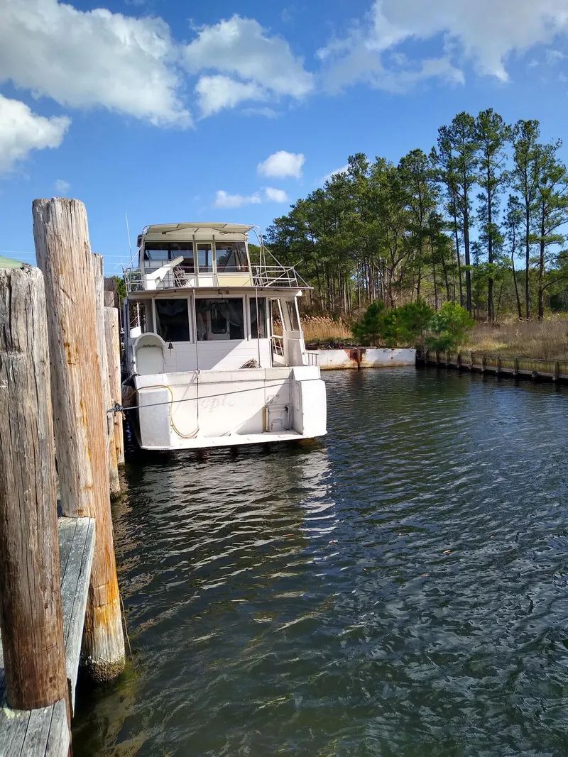 Slide: The Image of 1989 DeFever 57 POC Motor Yacht docked by wooden pier, surrounded by trees and blue sky. - 3