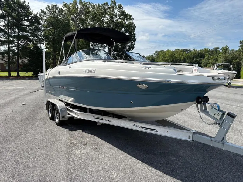 The Image of 2021 Stingray 231 DC boat on trailer, parked outdoors, under clear sky. - 1