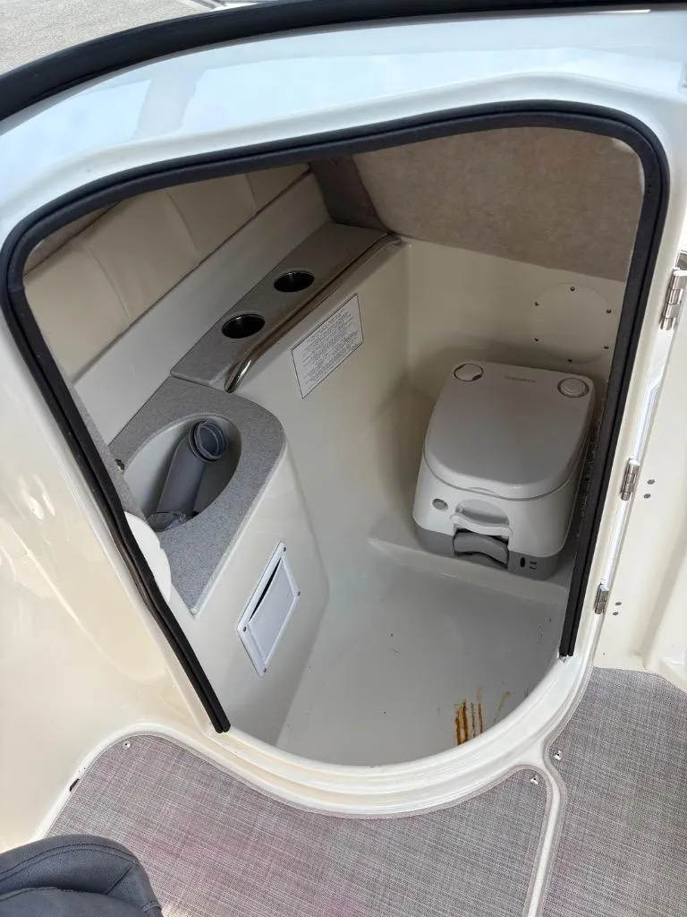 Slide: The Image of 2021 Stingray 231 DC boat interior with compact marine toilet and storage area. - 11