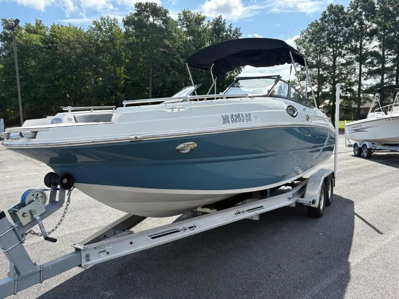 Slide: The Image of 2021 Stingray 231 DC boat on trailer, parked outdoors with trees in background. - 4