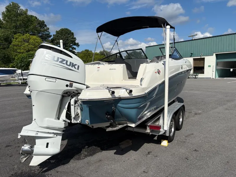 Slide: The Image of 2021 Stingray 231 DC boat with Suzuki outboard motor on a trailer, parked outdoors. - 7