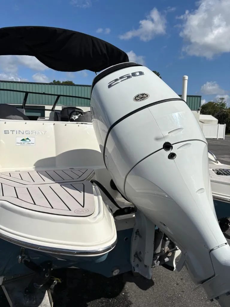 Slide: The Image of 2021 Stingray 231 DC boat with a 250 horsepower outboard motor, docked under a clear sky. - 8