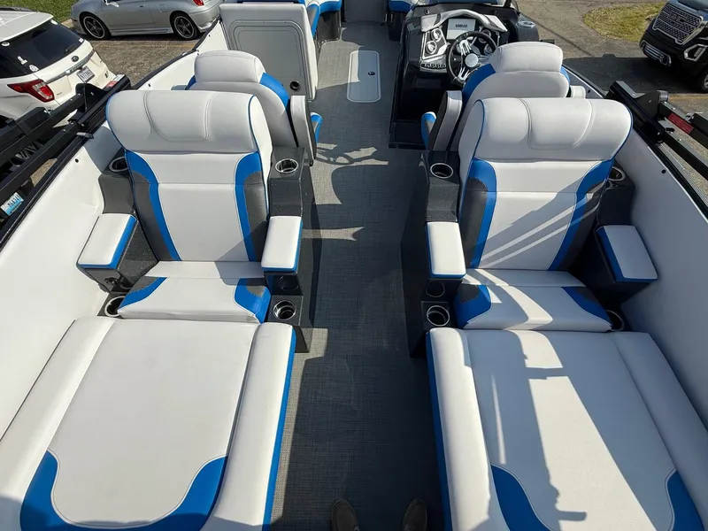 Slide: The Image of 2023 Crest Caribbean RS 230 boat interior with blue and white seating, cup holders, and steering console. - 5