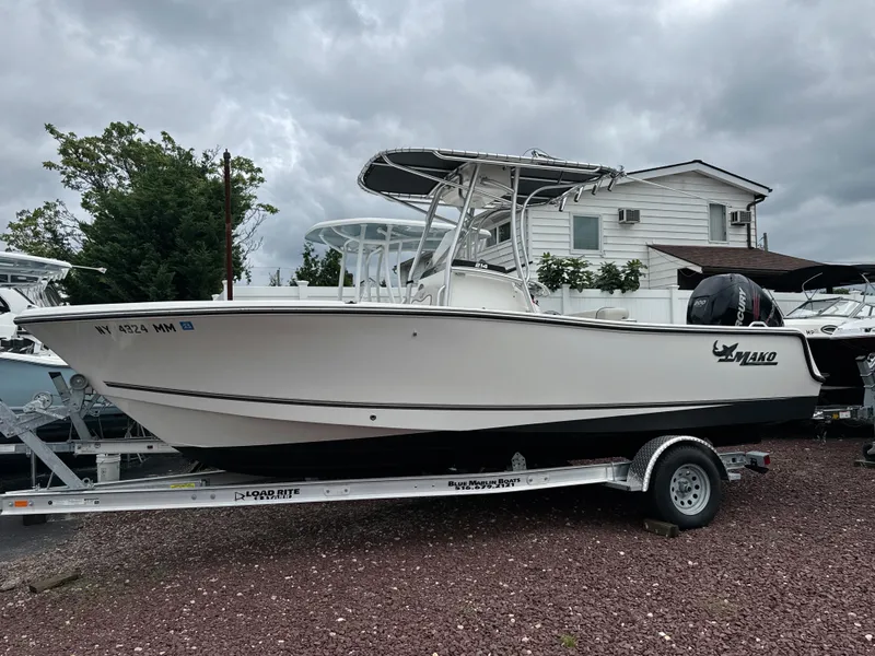Slide: The Image of 2017 Mako 214 CC boat on trailer, parked outdoors under cloudy sky. - 1