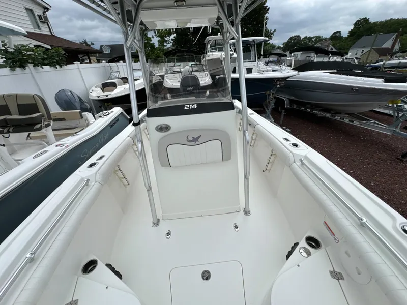 Slide: The Image of 2017 Mako 214 CC boat interior with white seating and console, parked among other boats. - 11