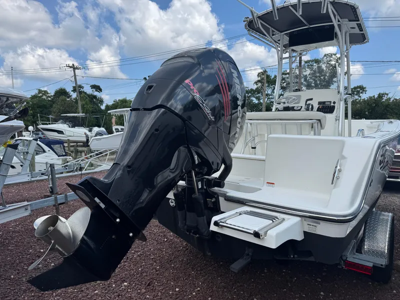 Slide: The Image of 2017 Mako 214 CC boat with Mercury outboard motor, parked on a trailer under a cloudy sky. - 3