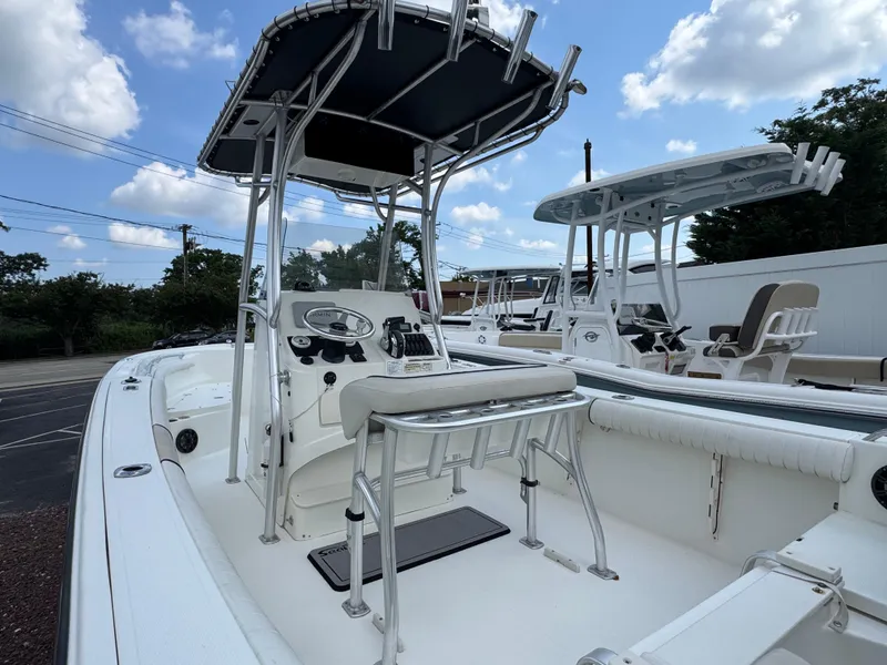 Slide: The Image of 2017 Mako 214 CC boat with T-top, console, and seating, under a blue sky. - 4