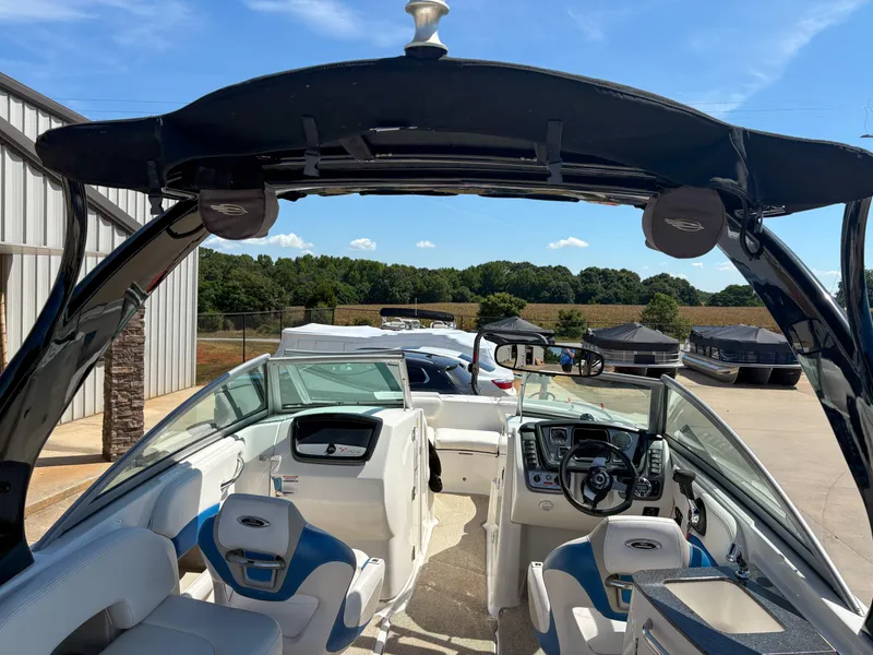 Slide: The Image of 2012 Chaparral 244 Xtreme boat interior with blue and white seating, parked outdoors. - 19