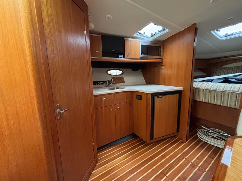 Slide: The Image of 2008 Tiara Yachts 3600 Open interior with wood cabinetry, kitchenette, and cozy sleeping area. - 11