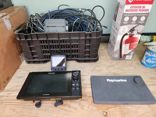 Slide: The Image of Raymarine navigation equipment and cables on a wooden surface, near a fire extinguisher box. - 42