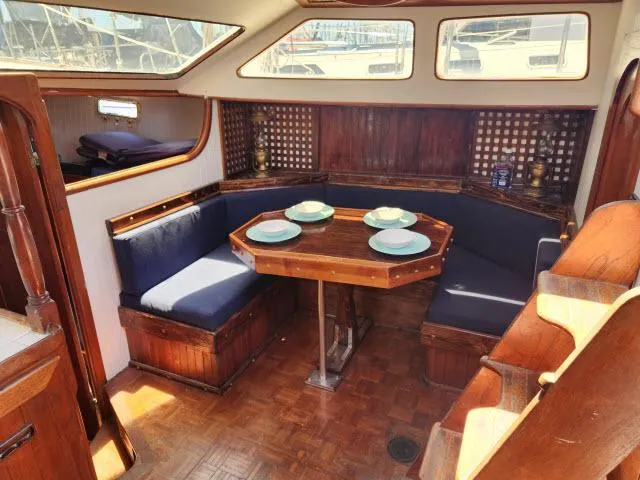 Slide: The Image of Interior of 1978 Hardin Voyager 44 sailboat with wooden dining area and blue cushions. - 5