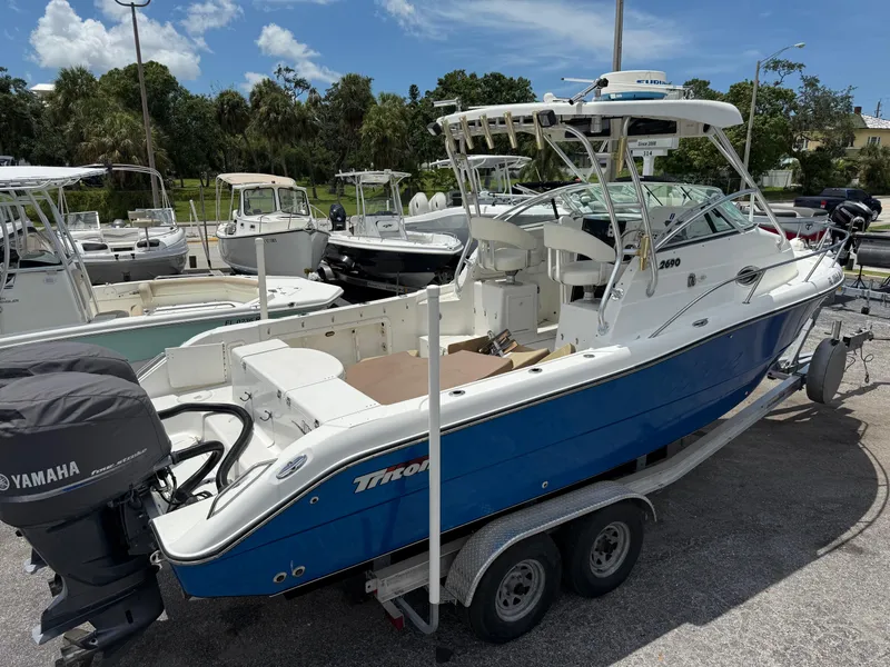 Slide: The Image of 2004 Triton 2690 WA boat with Yamaha engines, parked on a trailer in a marina. - 10