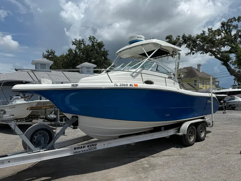 Slide: The Image of 2004 Triton 2690 WA boat on trailer, blue and white, parked outdoors. - 2