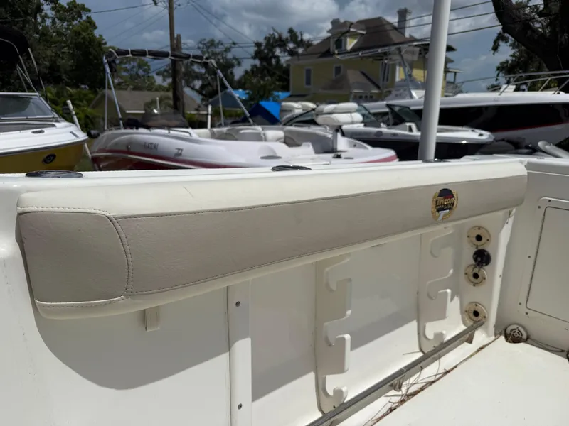 Slide: The Image of 2004 Triton 2690 WA boat interior with padded seating and rod holders, parked among other boats. - 22