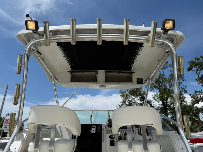 Slide: The Image of 2004 Triton 2690 WA boat cockpit with seating and rod holders under a clear blue sky. - 25