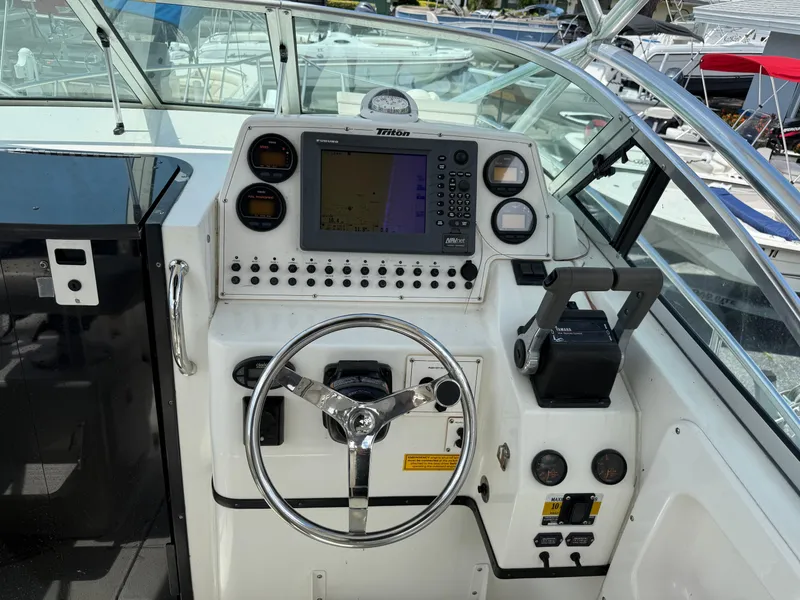 Slide: The Image of 2004 Triton 2690 WA boat dashboard with steering wheel and navigation controls. - 33