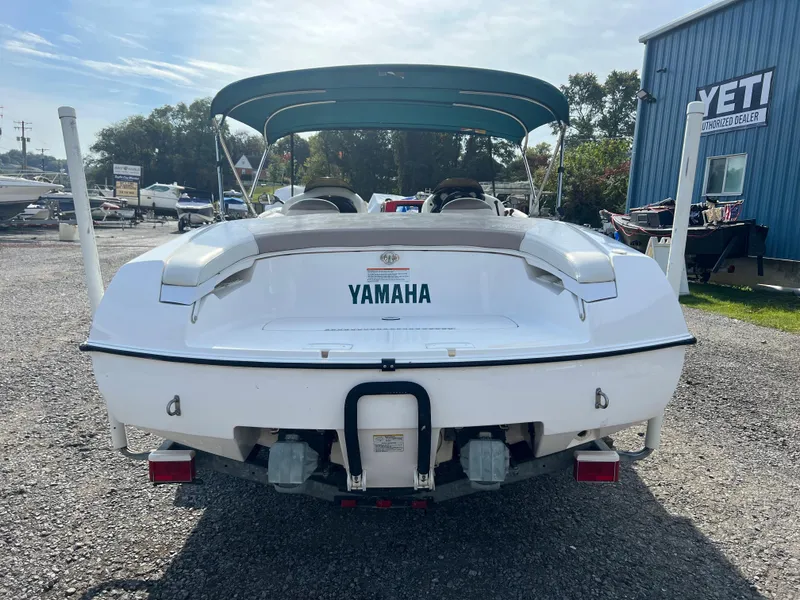 Slide: The Image of 2000 Yamaha LS 2000 boat with canopy, parked on gravel near a blue building. - 2