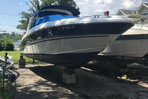 Slide: The Image of 2003 Sea Ray 29 Bow Rider boat on blocks, outdoors, under a partly cloudy sky. - 3