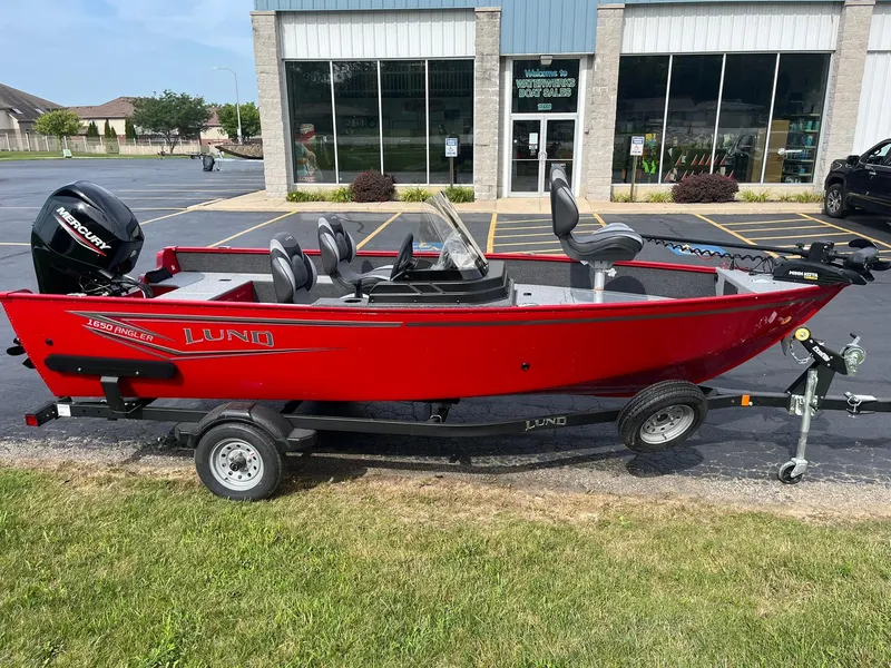 The Image of 2026 Lund 1650 Angler SS boat, red, on trailer outside dealership. - 0