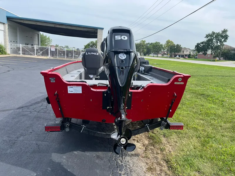 Slide: The Image of 2026 Lund 1650 Angler SS boat with a 50 HP motor, parked on pavement. - 2