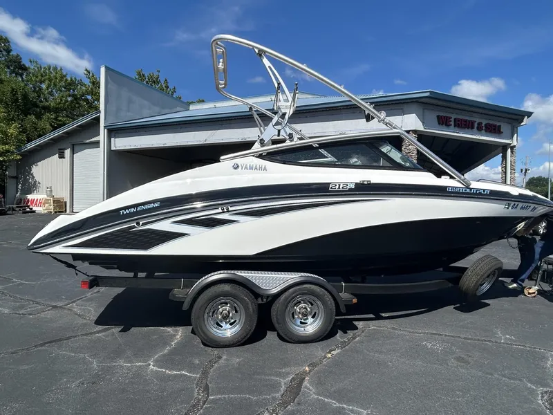 The Image of 2013 Yamaha Boats 212 X on trailer, parked outside a rental and sales shop. - 0