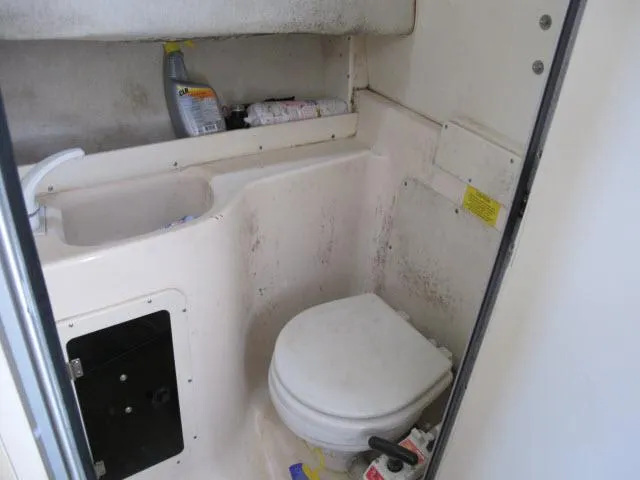 Slide: The Image of Interior of a 1997 Grady-White 258 Journey boat bathroom with toilet and cleaning supplies. - 19