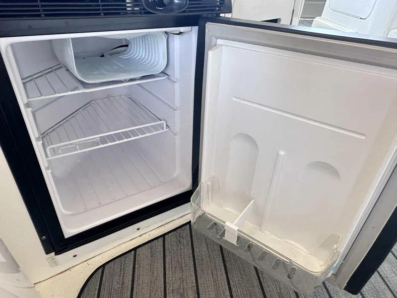 Slide: The Image of Open refrigerator inside 2007 Sea Ray 320 Sundancer boat, showing empty shelves and door storage. - 10