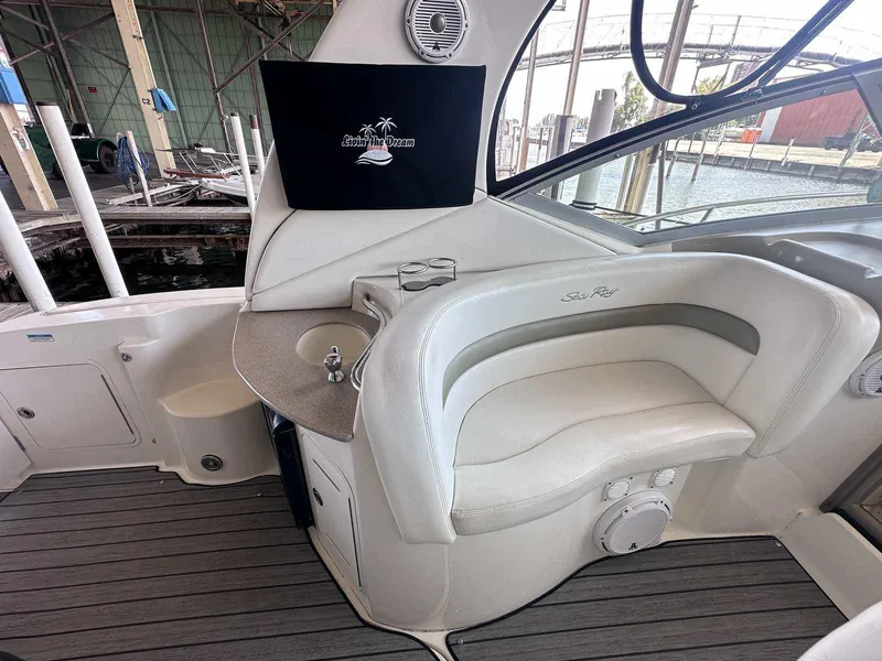 Slide: The Image of 2007 Sea Ray 320 Sundancer interior with seating, sink, and "Live the Dream" screen. - 11