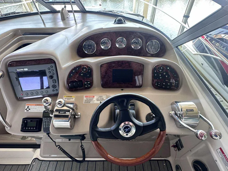 Slide: The Image of 2007 Sea Ray 320 Sundancer helm with steering wheel, gauges, and navigation controls. - 19