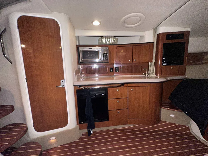 Slide: The Image of 2007 Sea Ray 320 Sundancer interior with kitchenette, wood cabinets, and modern appliances. - 26