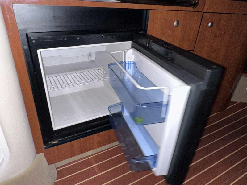 Slide: The Image of Open refrigerator inside 2007 Sea Ray 320 Sundancer boat, featuring wooden cabinetry. - 27