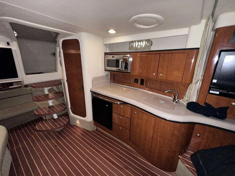 Slide: The Image of 2007 Sea Ray 320 Sundancer interior with kitchenette, wooden cabinets, and striped flooring. - 36