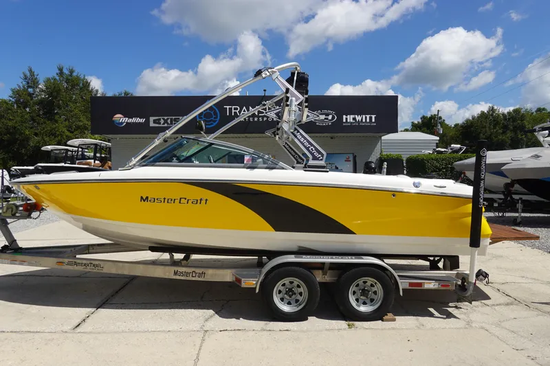 Slide: The Image of 2011 MasterCraft X15 boat in yellow on a trailer, parked outdoors under a blue sky. - 1