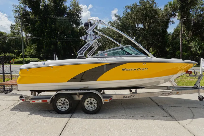Slide: The Image of 2011 MasterCraft X15 boat in yellow on a trailer, parked outdoors. - 4