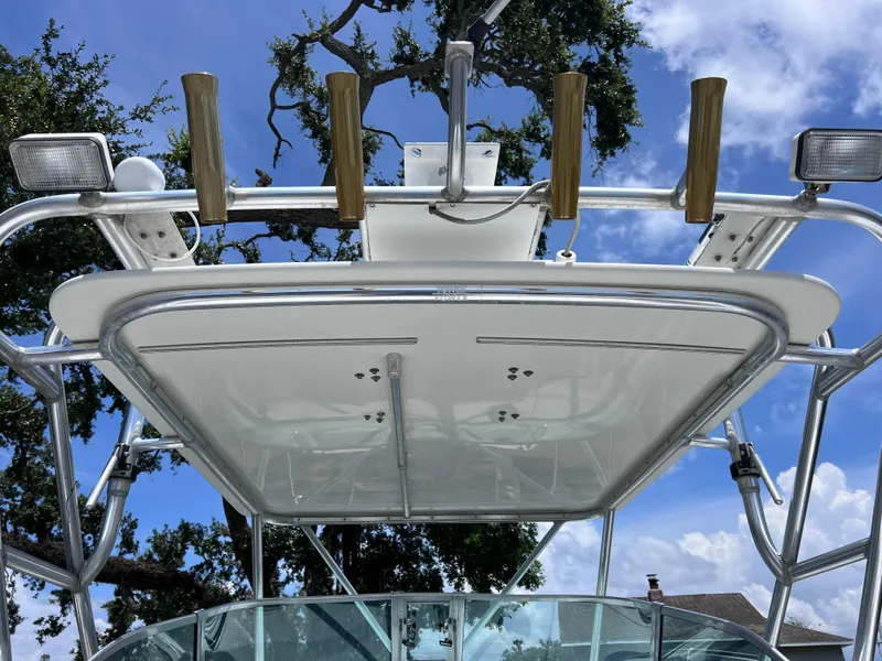 Slide: The Image of 1999 Glacier Bay 2670 Island Runner boat with rod holders and canopy under a blue sky. - 21