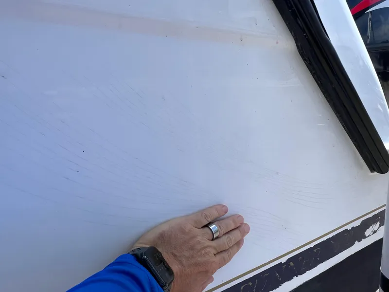 Slide: The Image of Hand touching the side of a 1999 Glacier Bay 2670 Island Runner boat. - 8