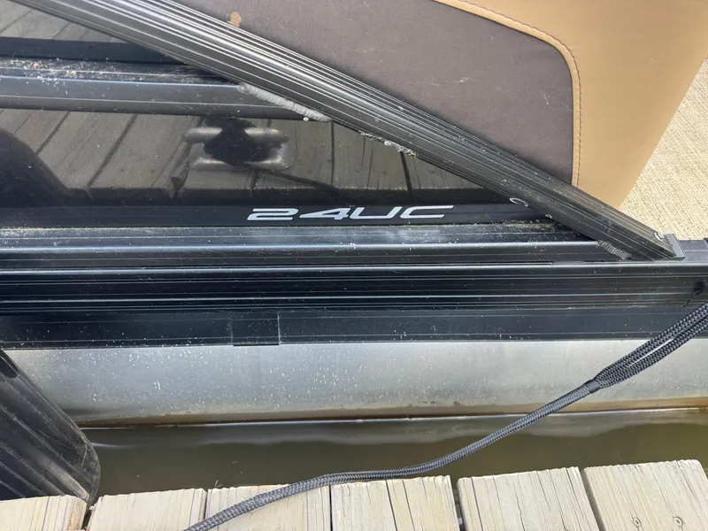 Slide: The Image of 2022 Barletta C24UC pontoon boat docked, showcasing sleek black exterior design. - 2