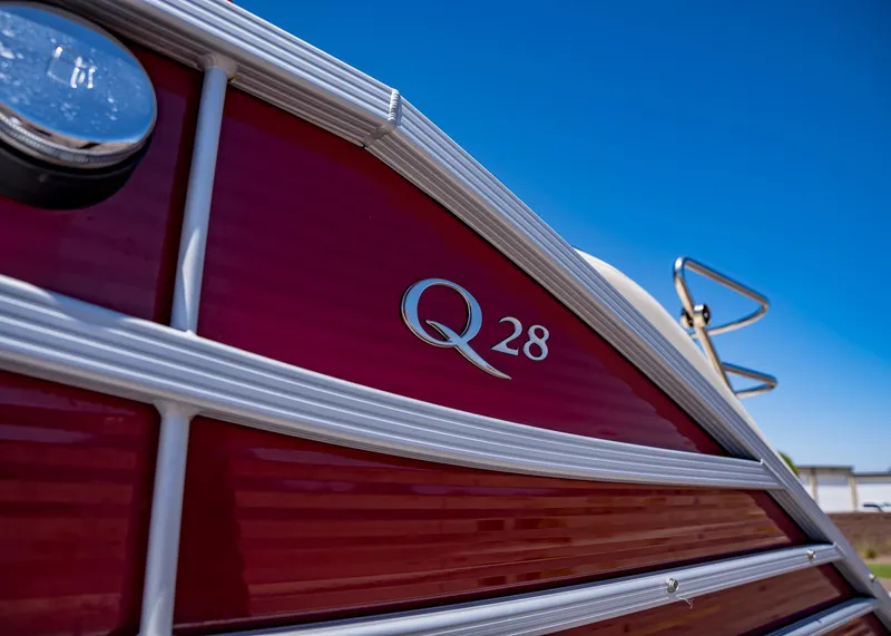 Slide: The Image of 2015 Bennington Q28 boat with red exterior and silver trim under clear blue sky. - 3