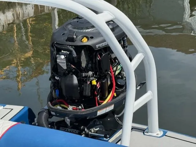 Slide: The Image of 2021 Glastron GX 210 Sport boat engine with open cover, docked on calm water. - 17